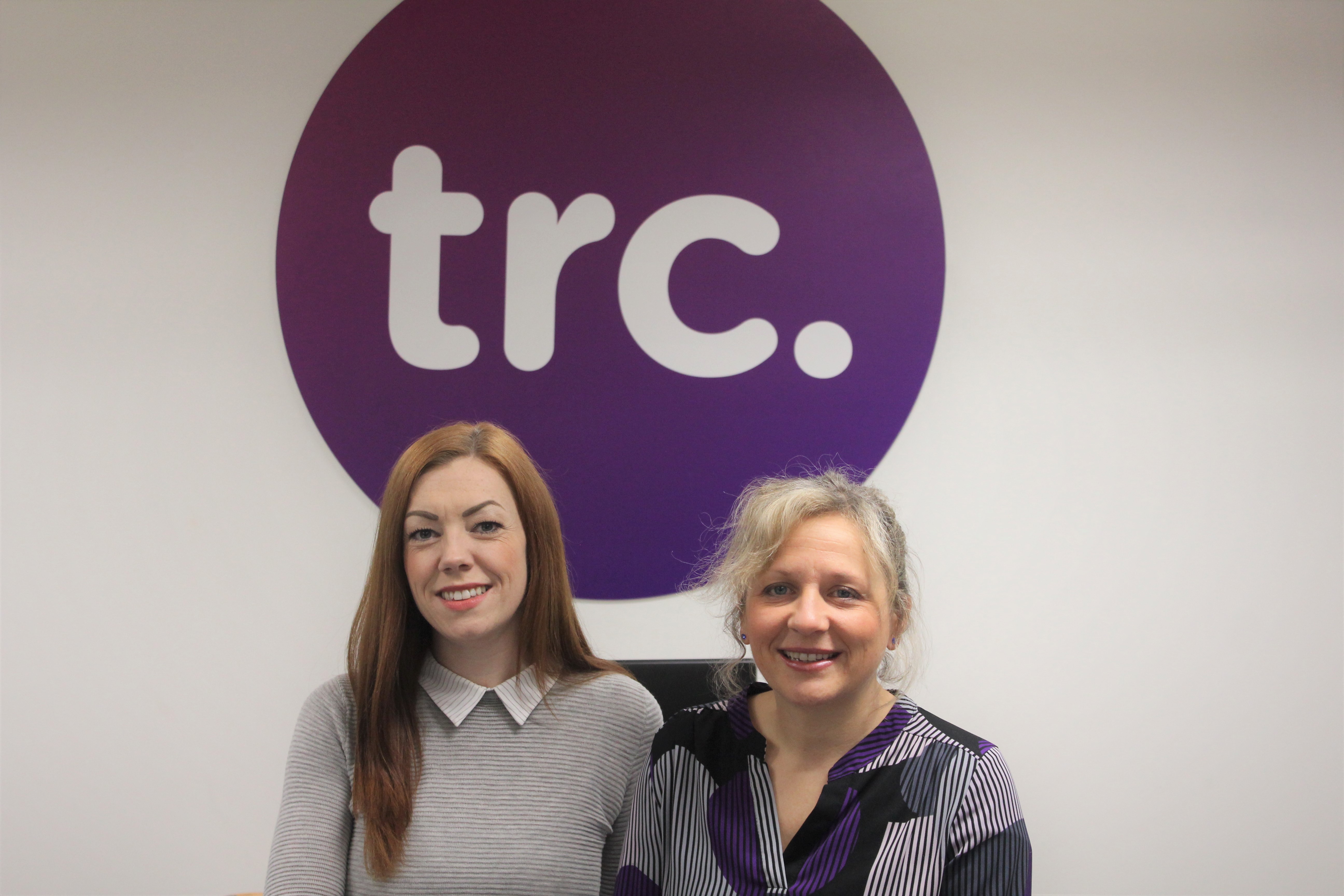 Caroline and Suzanne in front of TRC logo.